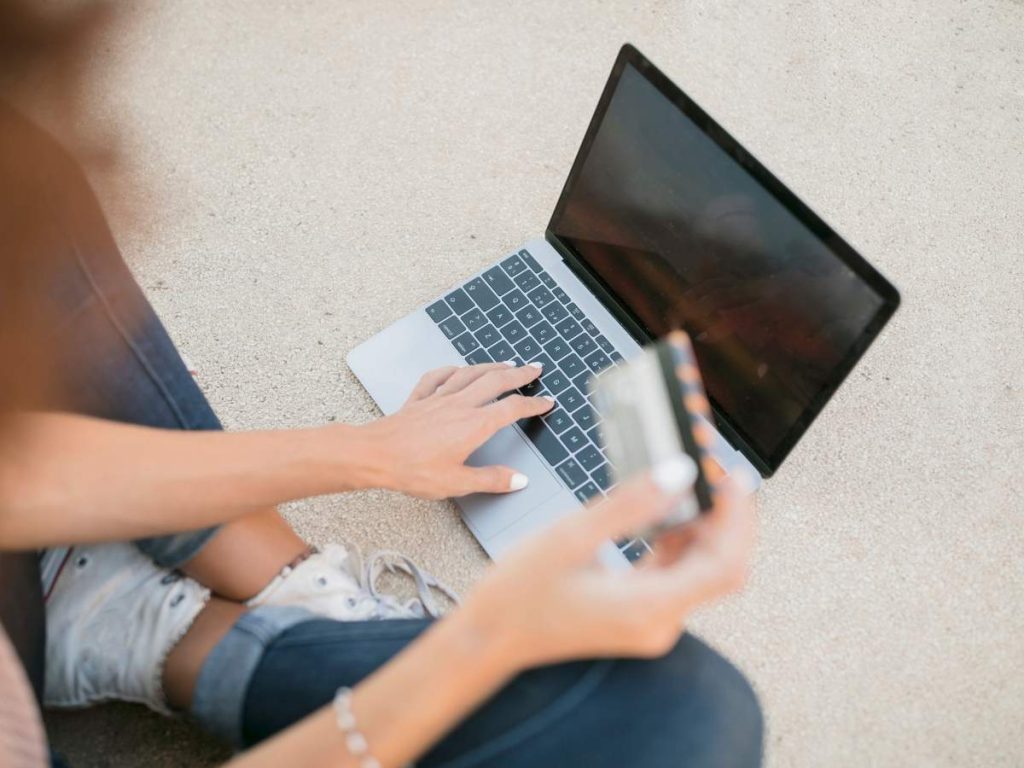 Dos estudiantes trabajando juntos en su TFG online utilizando una laptop en un ambiente informal.