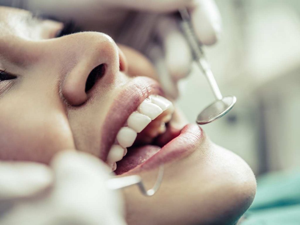 Dentista realizando revisión dental en paciente para TFG de Odontología